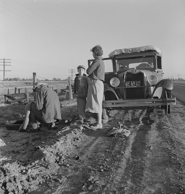 Migratory agricultural worker family making tire repairs along California Highway U.S. 99 