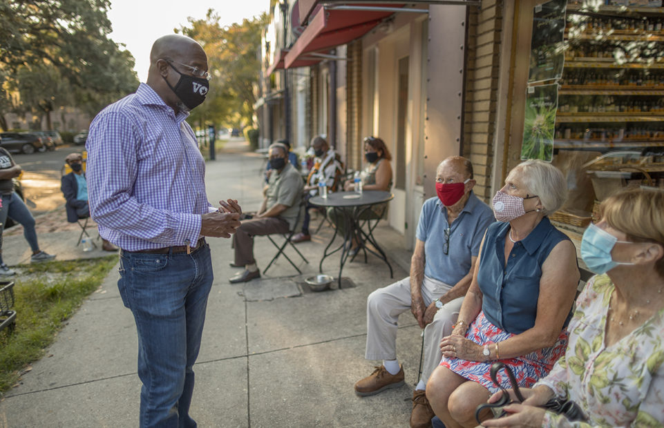 Raphael Warnock, left, wearing a mask, canvasses constituents before the election.