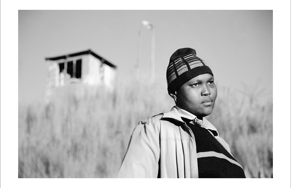 Black and white photo of a person standing against long grass