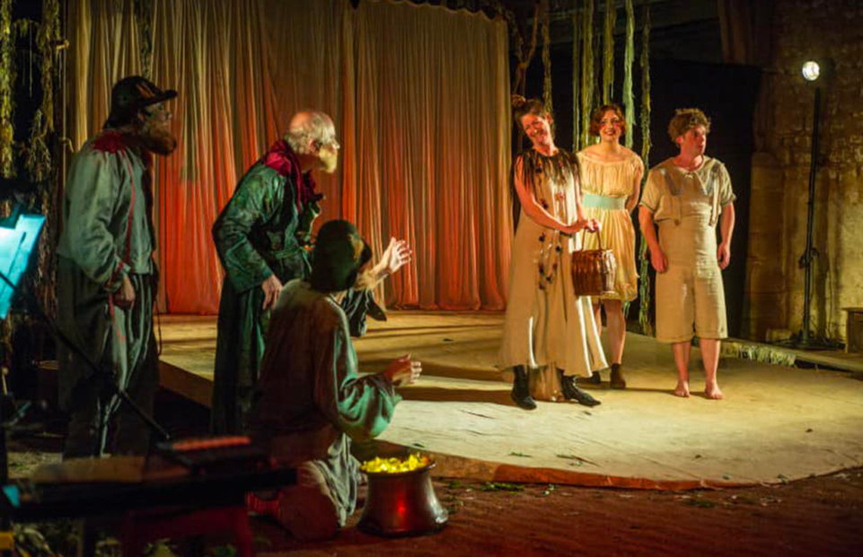 Actors in a performance of The Crock of Gold. On the left, two are dressed as leprechauns.