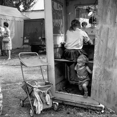 A small child running out of the door of a wooden booth.