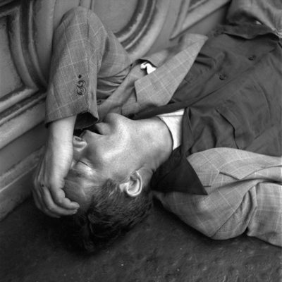 A man lying on the ground with his hand to his face