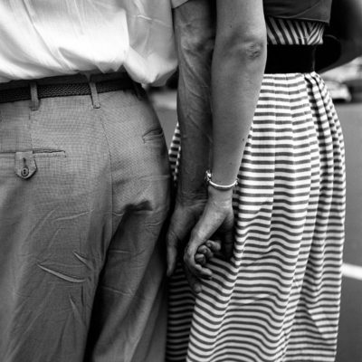 A man and a woman touching the backs of their hands. We only see them from waist to knees.