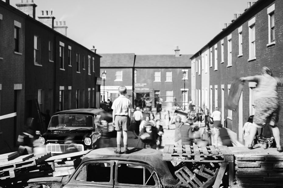 Buddy standing on top of a burnt out car, and other people participating in a barricade.