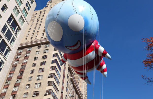 A humanoid balloon with a large blue head with visible stitching and a red-and-white romper suit.