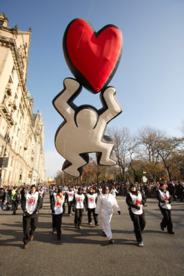 A balloon of a white human figure crouching and holding a red loveheart.