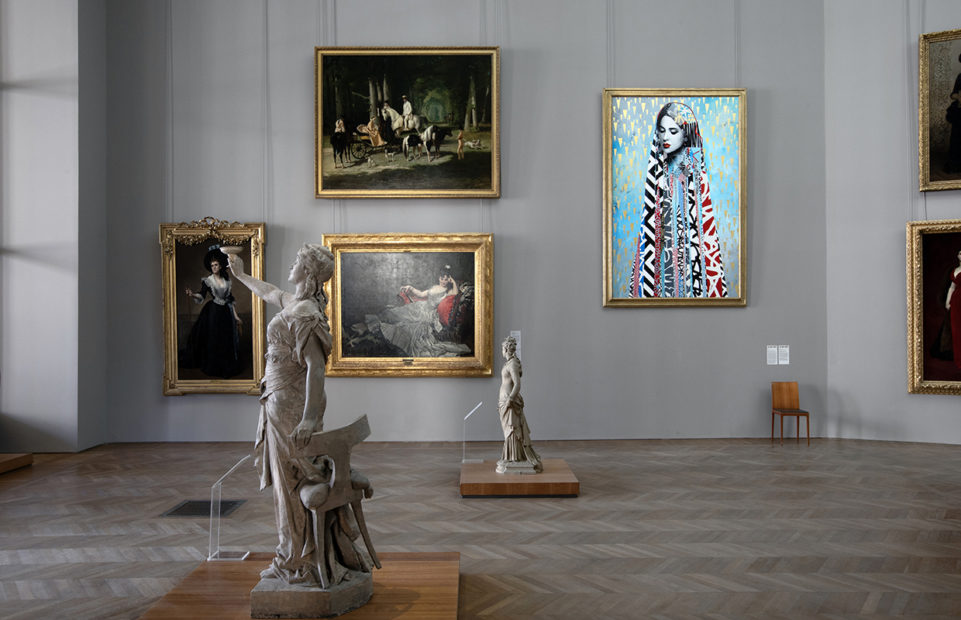 A bright modern urban art painting of a woman in multi-patterned textiles surrounded by gold rain in a room of traditional paintings and sculptures of women.