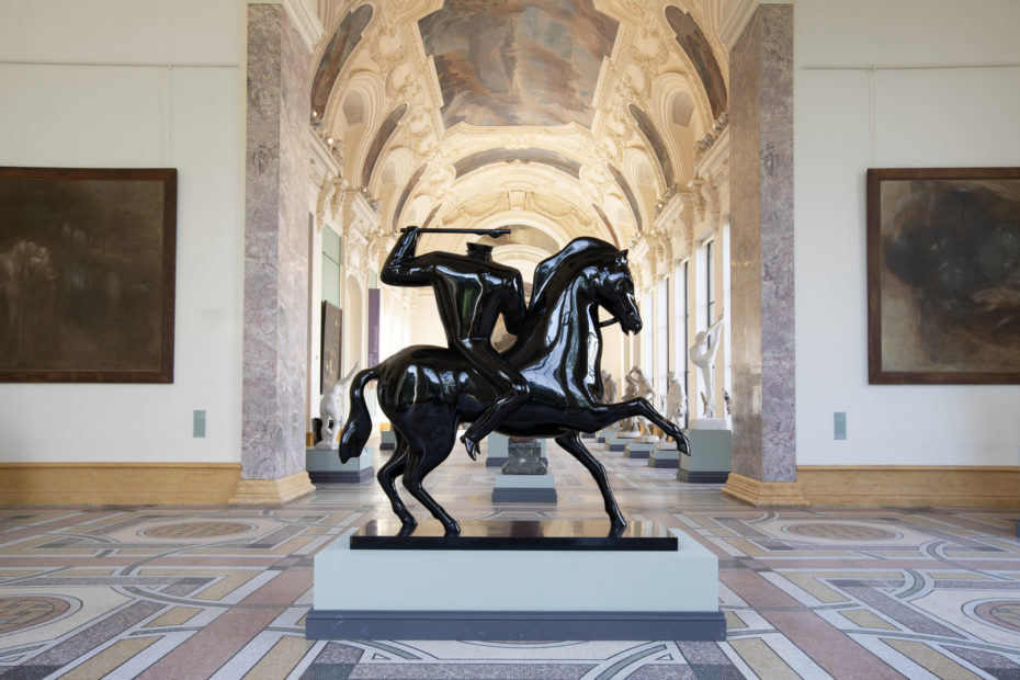 A headless statue of a man riding a horse and brandishing an axe.