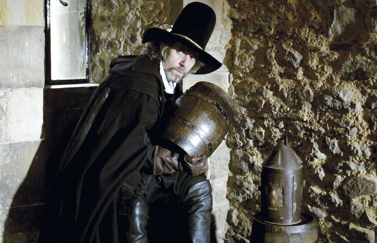 A reconstruction photo of Guy Fawkes in period clothes holding a barrel of gunpowder.