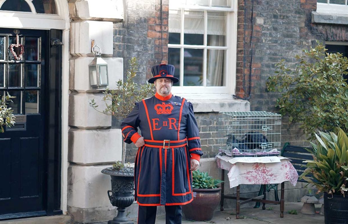 A Yeoman warder with the baby ravens in a cage.