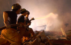 Three firefighters hosing down a smoky pile of debris at Ground Zero.