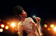 Jennifer Hudsent as Aretha Franklin in the film Respect. She is holding a microphone and singing.