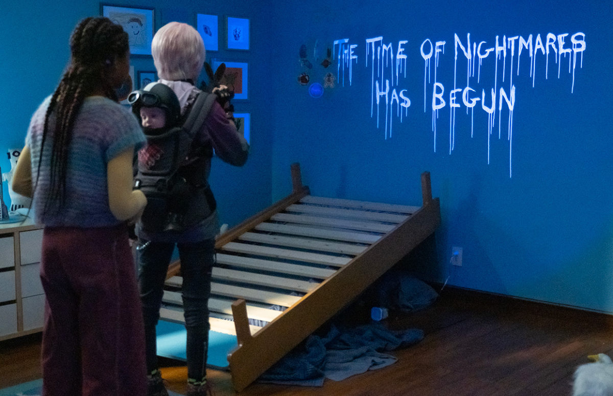 Two babysitter characters from the film look at a luminous message on a wall: The time of nightmares has begun.