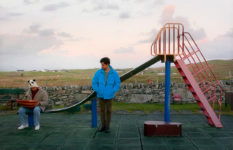 Two men in a children's playground, from the film Limbo.
