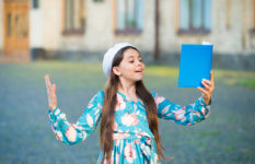 A teenager girl erciting from a book in the open air