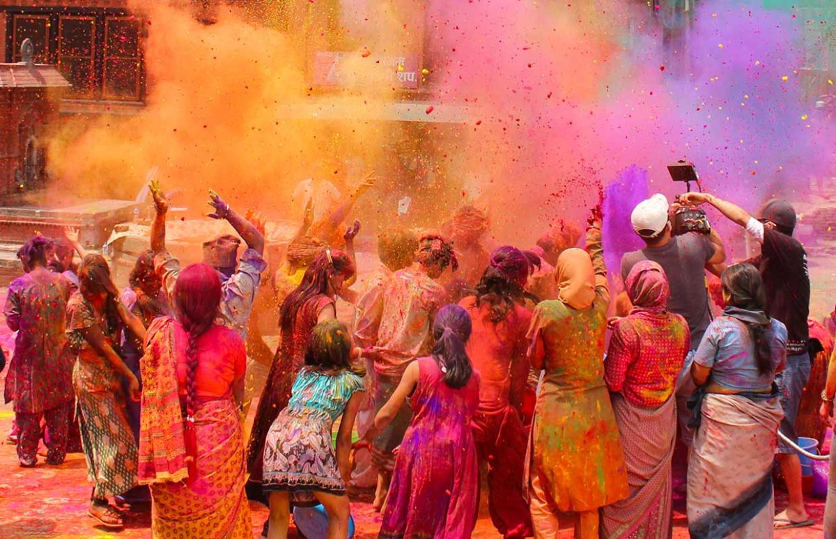 People participating in the Holi festival, throwing coloured powders and dressed in traditional Indian clothes
