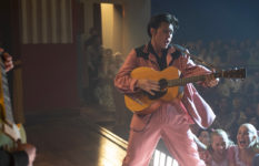 Elvis in a pink suit, playing guitar and singing