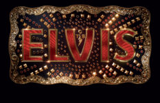 A belt buckle with ELVIS in red letters