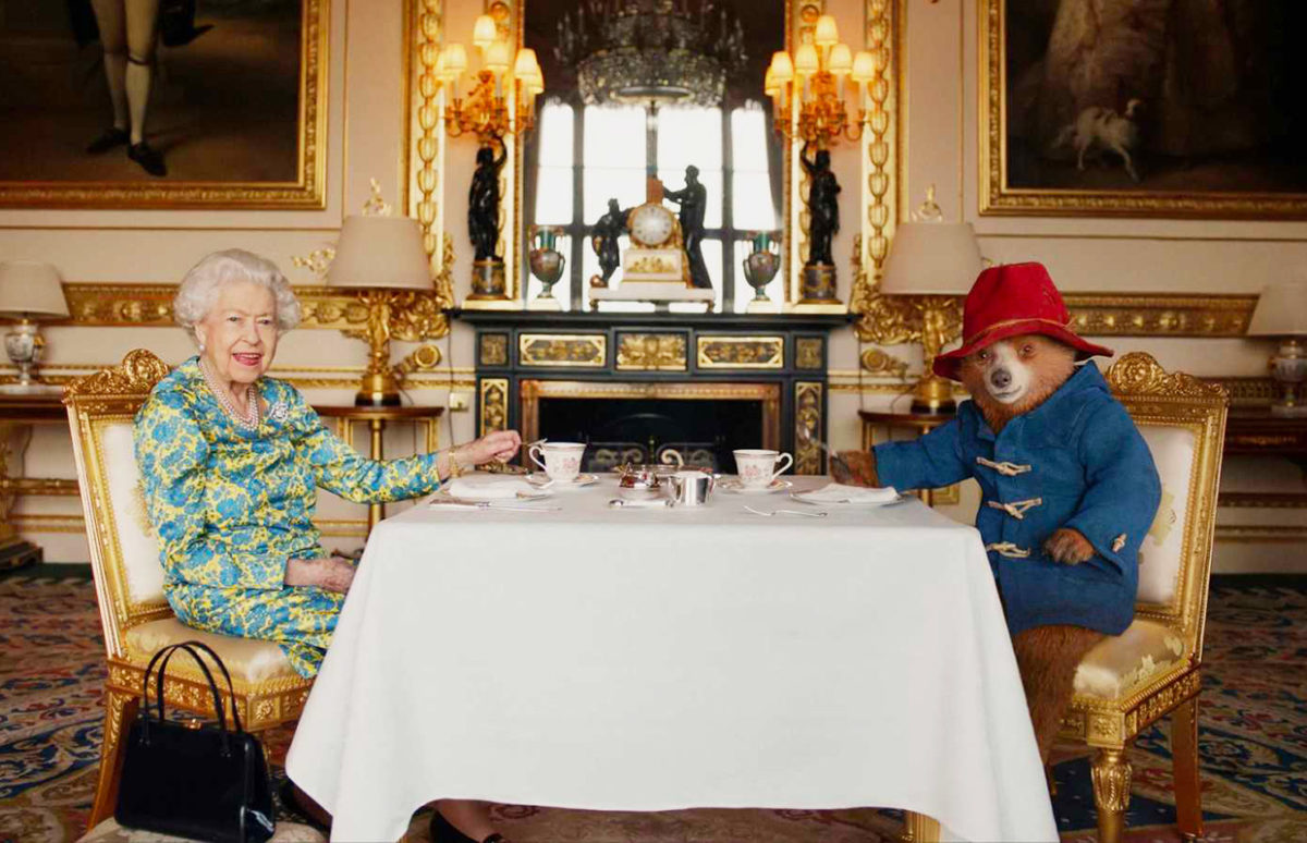 The Queen having tea at a table with Paddington Bear.