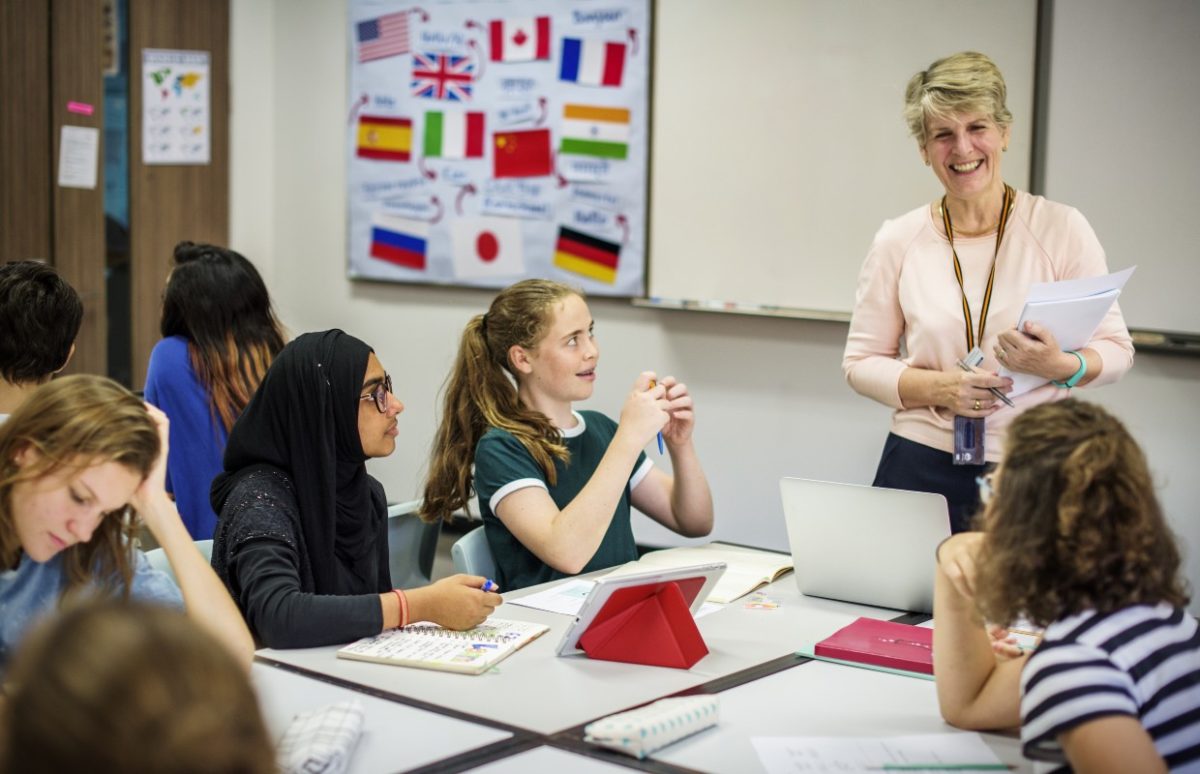 A teacher exchanging with a group of pupils in a language-teaching classroom.