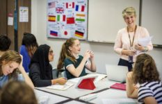 A teacher exchanging with a group of pupils in a language-teaching classroom.