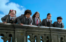 A group of children in school uniform looking angrily over a balustrade. Matilda, played by Alisha Weir, is in the centre.