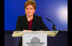 Nicola Sturgeon giving a press briefing at a lectern saying First Minister of Scotland