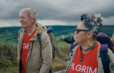 Jim Broadbent as Harold Fry, accompanied by another walker wearing the same Pilgrim T-shirt.