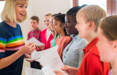 A teacher encouraging pupils who are singing in class.