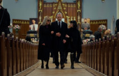 Madeline and Roderick Usher and Roderick’s second wife, Juno, played by Mary McDonnell, Bruce Greenwood and Ruth Codd walking up the aisle to leave the church after a funeral.