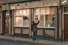 Dave Turner as TJ pushing a letter back into place in the sign of the pub The Old Oak.