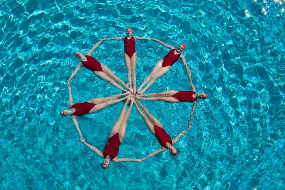 Seven synchronised swimmers making a star shape.