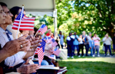 New citizens holding U.S. flags at the naturalisation ceremony at Springfield Armory National Historic Site in Massachusetts, 2023.