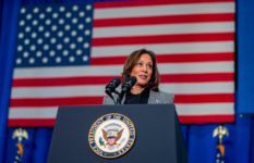 Kamala Harris giving a speech at a lectern, with a U.S. flag behind her.