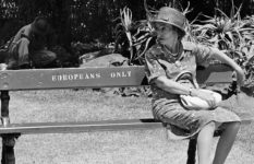 A woman sitting on a bench in South Africa markes Europeans only.