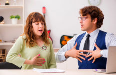 A woman and a man in a classroom seeming to practise breathing techniques.