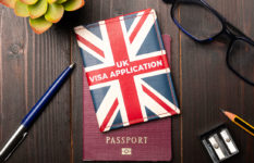 A Union Jack marked UK Visa Application sitting on a passport on a desk.