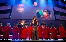 Katy Perry, singing with the Pasadena Chorale in front of pictures of firefighters.
