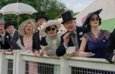 Members of the Crawley family in fancy hats shouting on horses at Ascot Races.